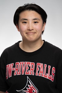 Sebastian Biebighauser Headshot. Male with black hair smiling at camera while wearing a black sweatshirt with UW-River falls text and a red falcon head