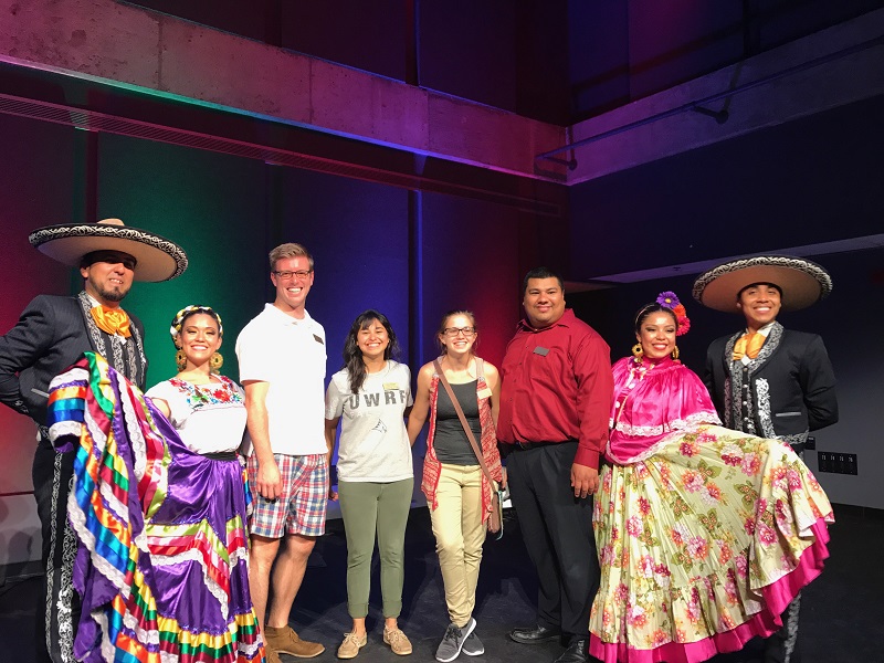 This is a photo of our four staff members and the four Ballet Folklorico Mexico Azteca performers at the Fall 2017 Mexican Independence Day Celebration event. The four performers are wearing traditional Folklorico dance attire. 