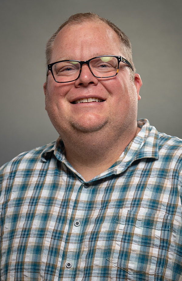 Headshot of Chris Holtkamp, white male with glasses and plaid shirt