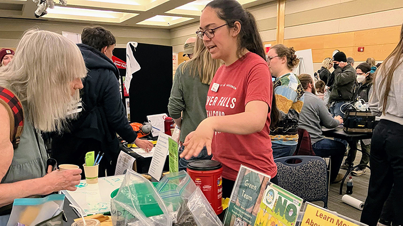 Kaitlin Ramirez, leader of the UW-River Falls Fair Trade Committee, discusses information related to sustainability with an attendee of Earth Fest at the university on April 22. 