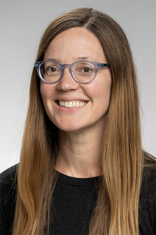Headshot of Melanie Ayres, a white female with long light brown hair wearing glasses and a black top
