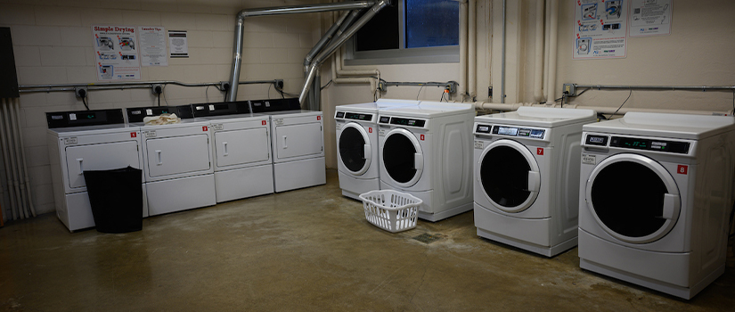 The laundry room in the basement of Crabtree hall has four washers, four dryers, and a large table and chairs.