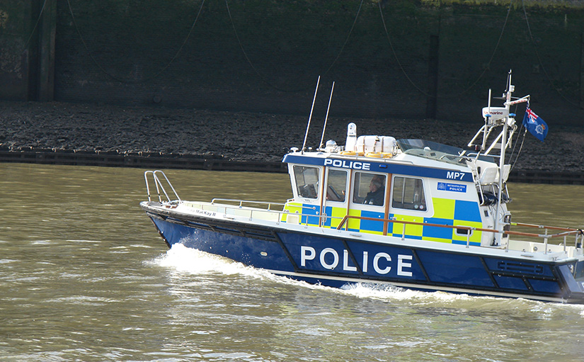 London police boat on the River Thames during low tide