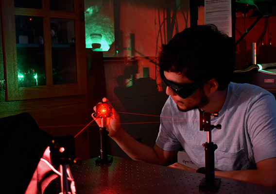 A male student conducts an experiment with lasers