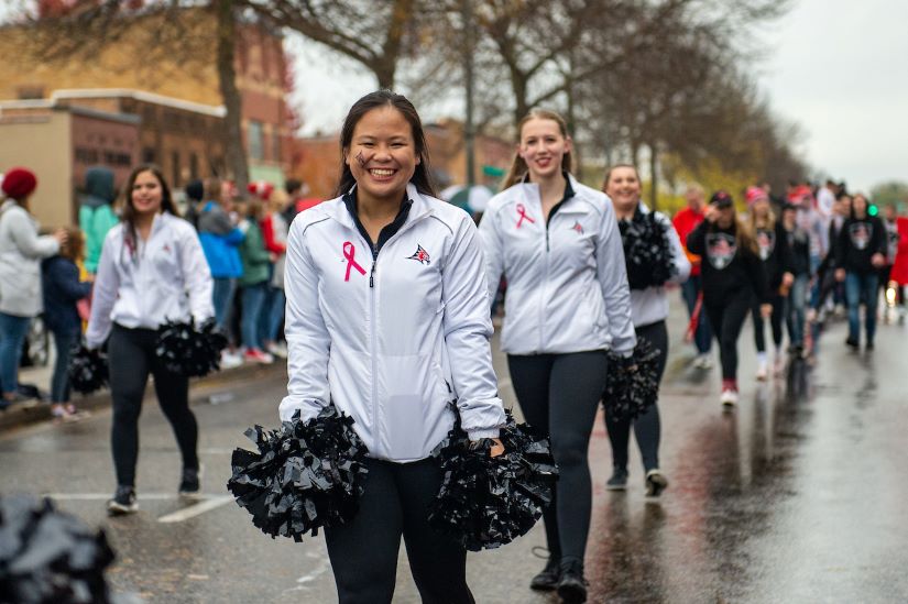 Members of the UWRF Cheer Team smile at the camera as they walk in the Homecoming Parade