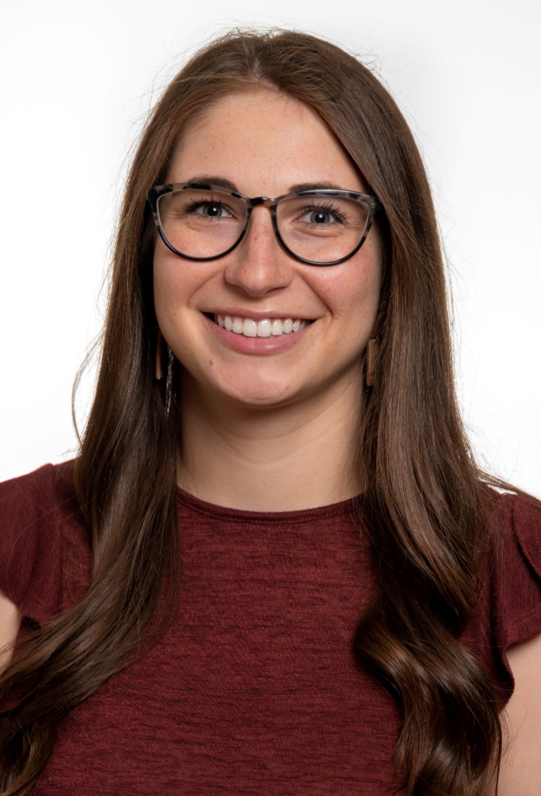 photo of katy putzker, brown hair, glasses, wearing maroon shirt and smiling