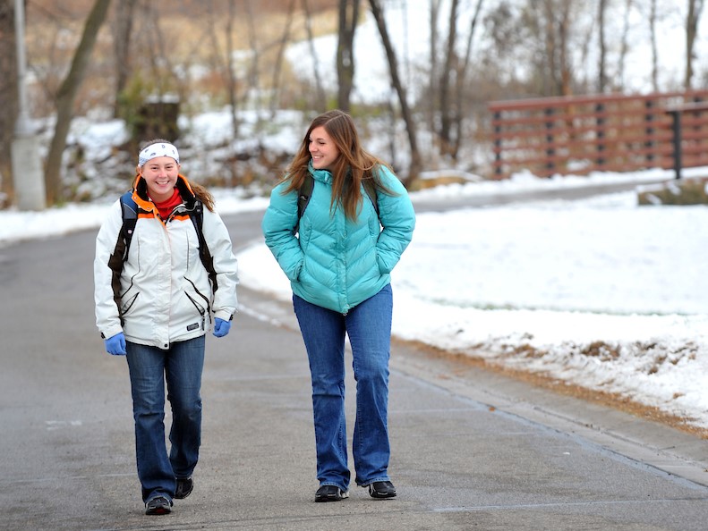 Two students walking in snow on campus 