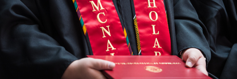 Graduating McNair Scholar holding diploma 