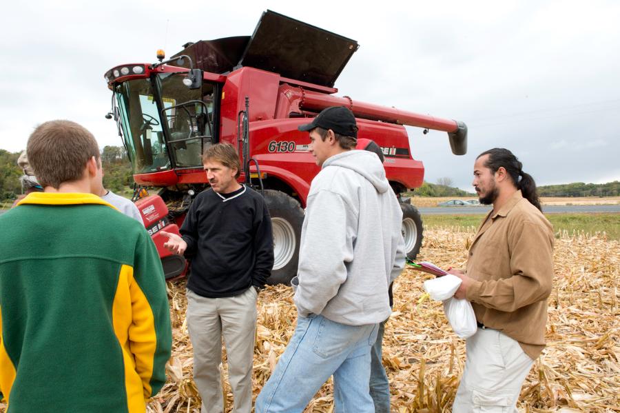 Students listen to instructor in cornfield. 