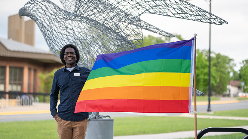 Alan Toussaint, Diversity, Inclusion and Belonging Pride specialist, places the LGBTQIA+ flag for Pride Month at UWRF’s Rodli Hall. 