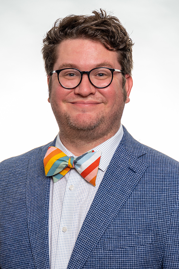 Headshot of Erik Kline, white male with blue jacket, glasses and bowtie