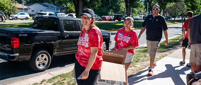 Volunteers help carry an item into the residence hall