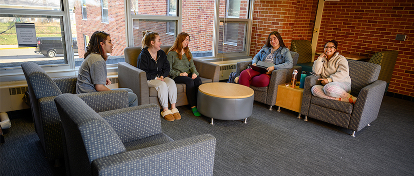 Multiple students talk in a floor lounge within Crabtree hall