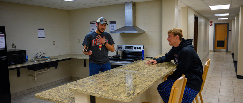 Two students talk in the McMillan Hall basement kitchen