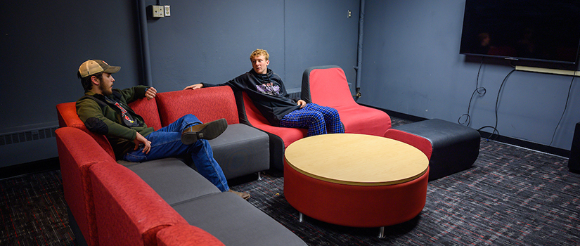 Two students hang out on lounge furniture in the McMillan Hall media room