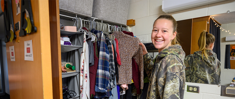 A student smiles while reviewing clothing in her closet in Hathorn hall