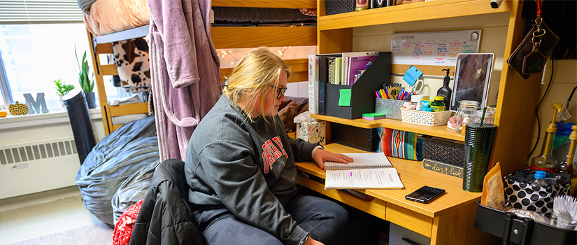 A student reviews homework while seated at their Hathorn hall room desk