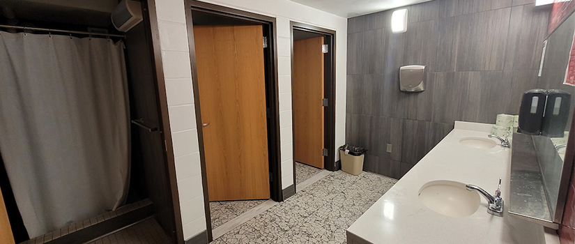 J McMillan Hall bathroom has multiple private shower rooms and toilet rooms with two sinks next to each other. Mirrors and hand dryers are also in the bathrooms.