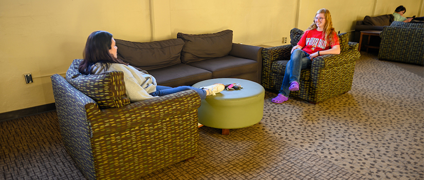 Two students chat in the Johnson Hall basement lounge