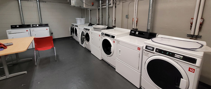 May Hall laundry room includes multiple washers and dryers as well as a table with chairs