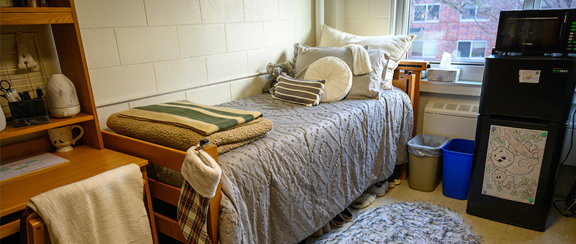 A bedroom in Prucha Hall with two desks, beds, and a minifridge/microwave unit