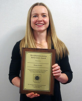 Woman with shoulder length blonde hair holding a plaque.