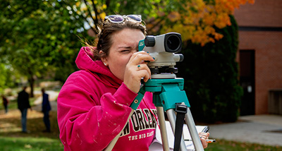 Environmental Engineering student looks through surveying equipment
