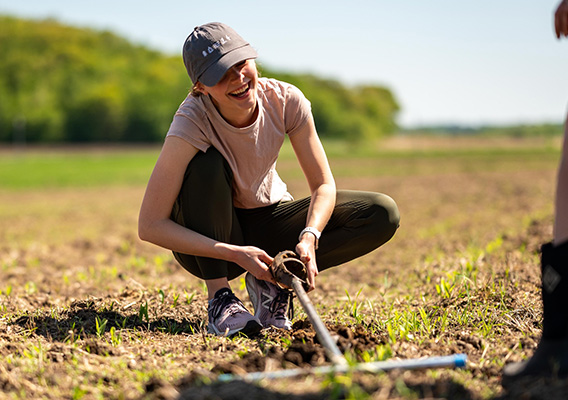 Agricultural Studies student kneels in a field