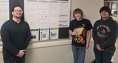 three male students stand in front of a poster display about AI