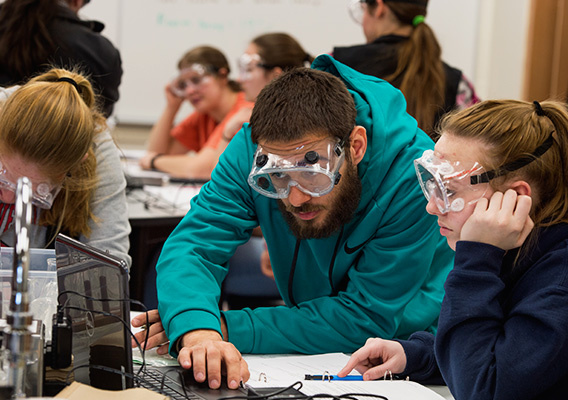 Two students complete a chemistry experiment in class