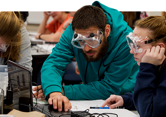 Two students complete a chemistry experiment in class