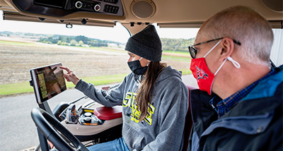 Agriculture Student pointing to a computer screen inside a Farming Tractor