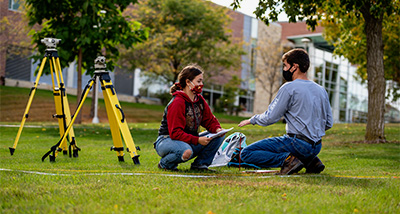 Two Students working with land surveying equipment
