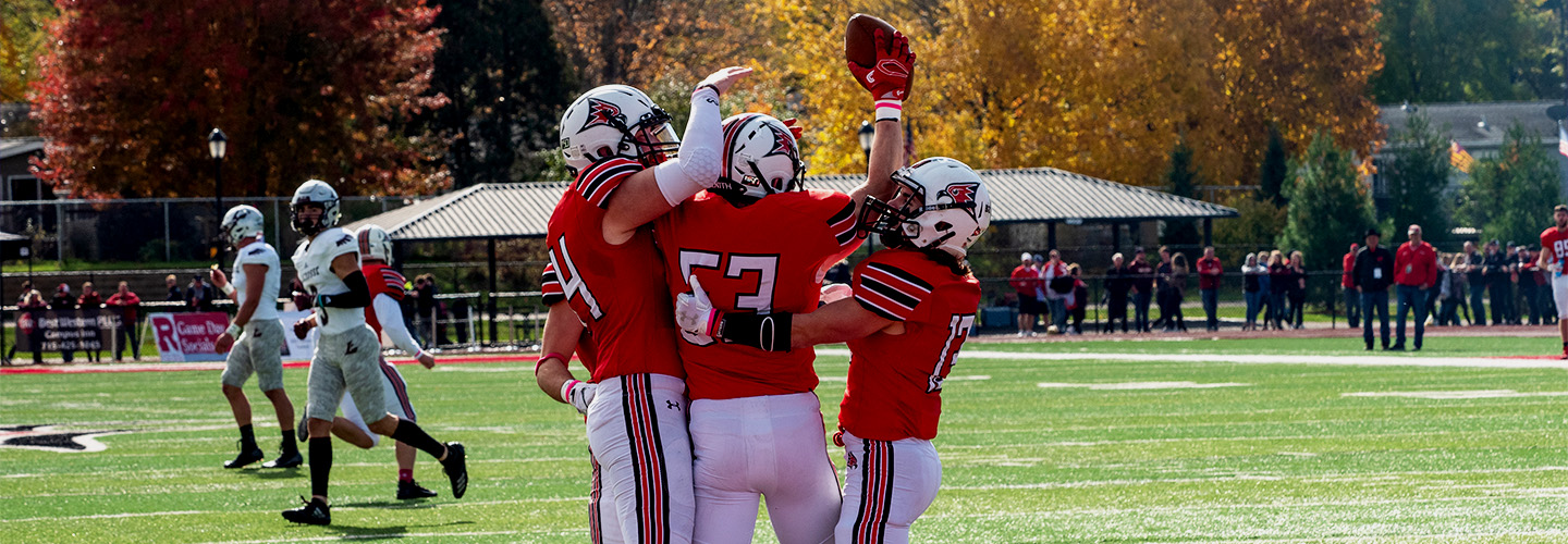 Three football players celebrate a touchdown