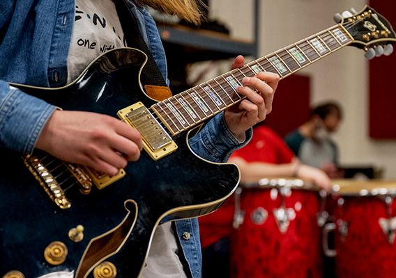 Band student strums a guitar during rehearsal