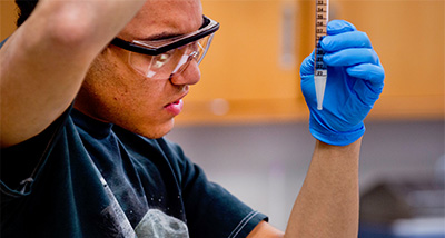 Biotechnology student using pipette to fill a vial
