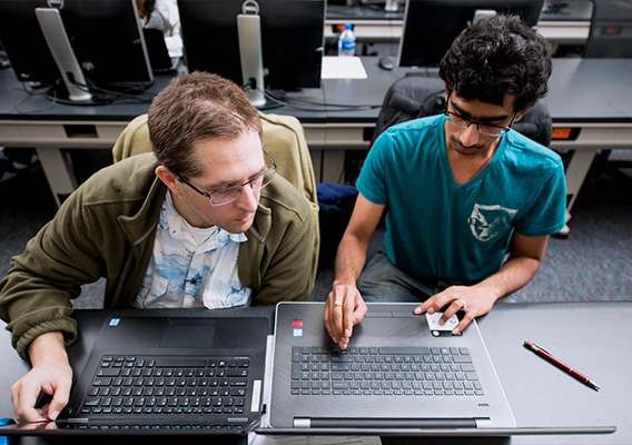 Two graduate students work together on a project during class