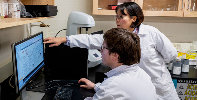 Lab Professor points to a document on a student's computer screen
