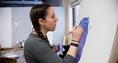 Student paints on canvas during an art class