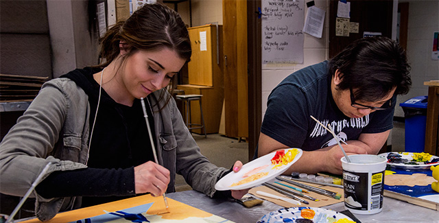 Student paints on canvas during an art class