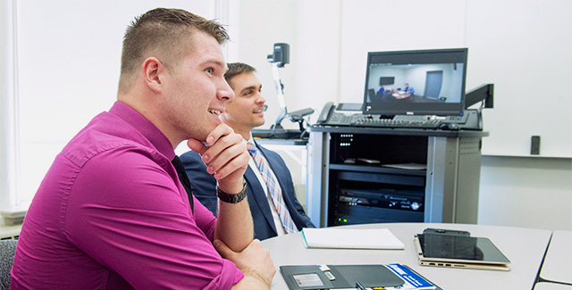Two students listen to their Sales professor during class