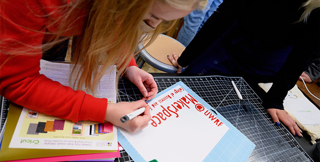 Student in the MakersSpace removes excess vinyl off of a sheet