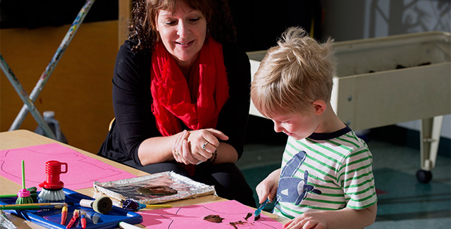 Student helps a child draw during a student teaching lesson