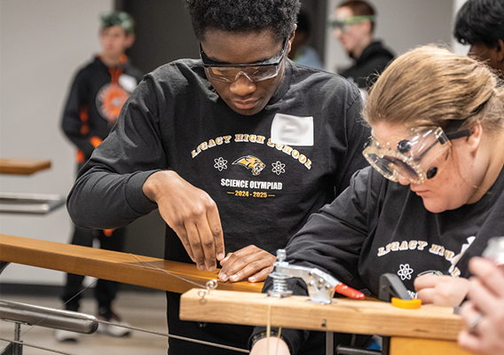 a male and female student work together to create a device as part of the Science Olympiad Border Battle
