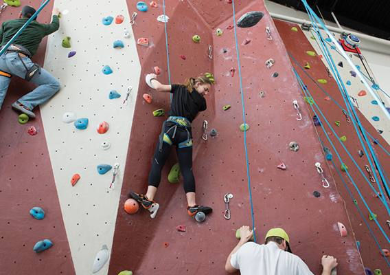 three students use the climbing wall