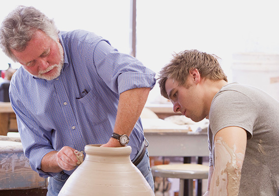Ceramics professor helps a student with their clay pot