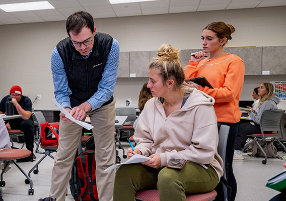 A Clinical Exercise Physiology professor points to a graph on a sheet of paper for a student to read
