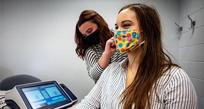 Communication Sciences student inspects the ear canal of another student