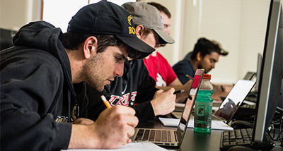 Computer Science student studies their laptop while taking notes