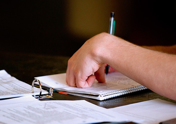 A student studying for a test by writing in their notebook